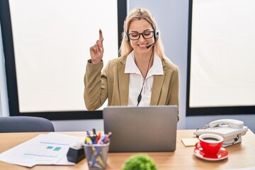 Poster - Young caucasian woman working wearing call center agent headset smiling with an idea or question pointing finger with happy face, number one