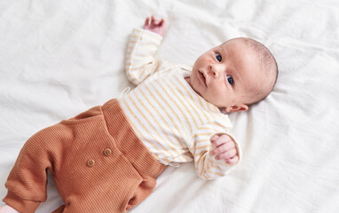 Adorable caucasian baby lying on bed at bedroom