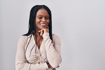 Sticker - African woman with braids standing over white background with hand on chin thinking about question, pensive expression. smiling and thoughtful face. doubt concept.