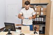 © Krakenimages.com - Young hispanic man smiling confident make photo to package label at storehouse