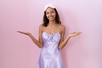 Poster - Young hispanic woman wearing sleep mask and nightgown smiling cheerful offering hands giving assistance and acceptance.