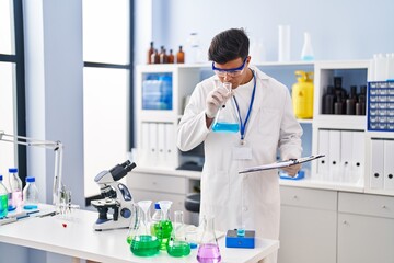 Sticker - Young hispanic man scientist smelling liquid on test tube at laboratory