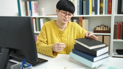 Wall Mural - Young chinese woman student holding book studying at library university