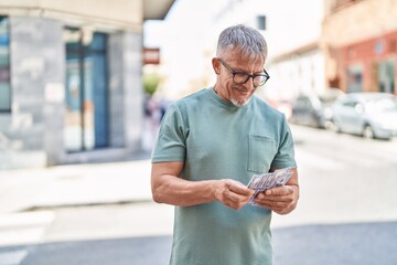 Sticker - Middle age grey-haired man smiling confident counting dollars at street