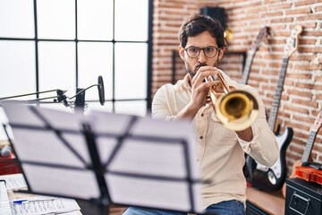 Wall Mural - Young hispanic man musician playing trumpet at music studio