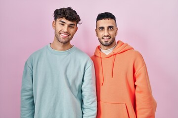 Canvas Print - Young hispanic gay couple standing over pink background with a happy and cool smile on face. lucky person.