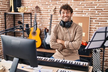 Poster - Young man musician smiling confident sitting with arms crossed gesture at music studio