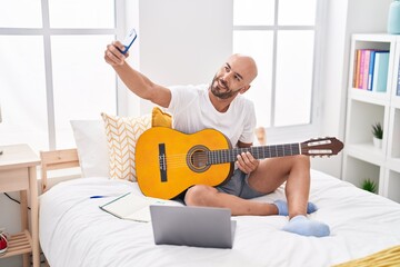 Sticker - Young bald man playing classical guitar make selfie by smartphone at bedroom