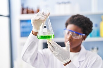 Poster - African american woman wearing scientist uniform measuring liquid at laboratory