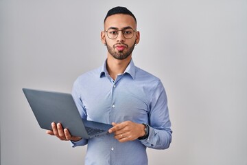 Poster - Young hispanic man working using computer laptop looking at the camera blowing a kiss on air being lovely and sexy. love expression.