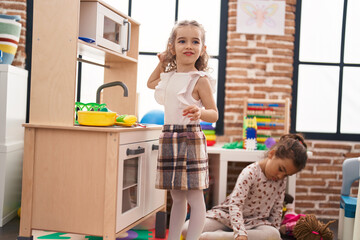 Poster - Two kids playing with play kitchen standing at kindergarten