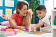 © Krakenimages.com - Teacher and toddler playing with maths puzzle game sitting on table at kindergarten