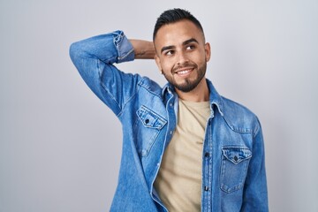 Canvas Print - Young hispanic man standing over isolated background smiling confident touching hair with hand up gesture, posing attractive and fashionable