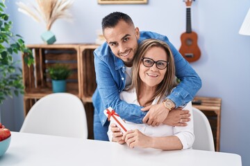 Canvas Print - Man and woman mother and son surprise with gift hugging at home