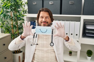 Sticker - Handsome middle age doctor man wearing safety mask smiling with a happy and cool smile on face. showing teeth.