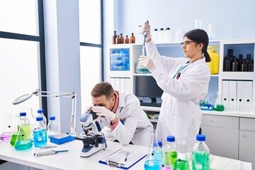 Man and woman wearing scientists uniform working at laboratory