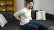 © Krakenimages.com - Young hispanic man suffering for backache sitting on sofa at home