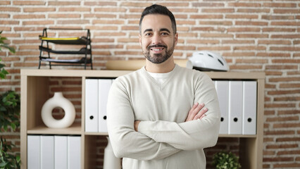 Canvas Print - Young hispanic man business worker smiling confident standing with arms crossed gesture at office