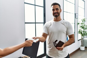 Poster - Young hispanic man customer paying purchase using credit card at clothing store