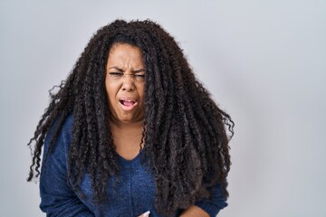 Sticker - Plus size hispanic woman standing over white background with hand on stomach because nausea, painful disease feeling unwell. ache concept.