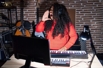 Sticker - Plus size hispanic woman playing piano at music studio shouting and screaming loud to side with hand on mouth. communication concept.