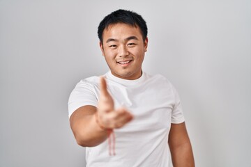 Sticker - Young chinese man standing over white background smiling cheerful offering palm hand giving assistance and acceptance.