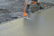 © ungvar - Using trowel worker plasters wet concrete cement floor after it has been poured