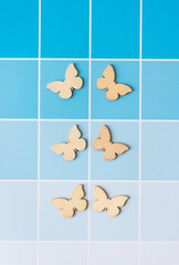 Wall Mural - six wood butterfly cutout ornaments on blue paper sheet with paint-chip coloration