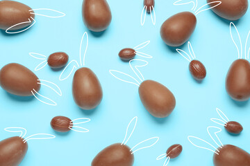 Wall Mural - Many chocolate Easter eggs with drawn bunny ears on light blue background