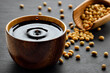 soy sauce with spalsh and drop in wooden bowl and dry soybeans in scoop