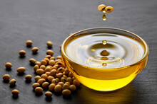 Soybean Oil Dripping From Beans In Bowl And Soy Seeds On Black Stone Background