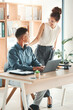 © Allistair F/peopleimages.com - Office, man and woman at desk, support and motivation from management at startup, working together on project. Laptop, ideas and partnership, Businessman and mentor in collaboration on job proposal.