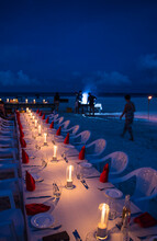 Candles Burning On Dinner Table Set On Coastal Beach, Maldives