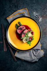 Wall Mural - Pieces of beef fillet steak with asparagus, parmesan, tomatoes and demiglas sauce. Beef tenderloin dish served on a yellow plate, top view