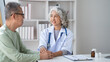 © Parichat - Expert Asian senior female doctor talking with her male patient show support and care.