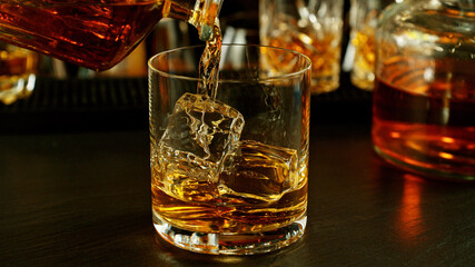 Poster - Detail of pouring whiskey into glass with ice cubes.