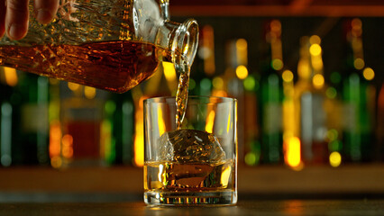 Poster - Detail of pouring whiskey into glass with ice cubes.