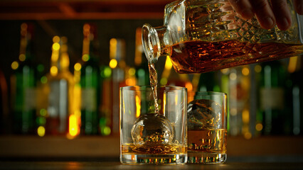 Wall Mural - Detail of pouring whiskey into glass with ice cubes.