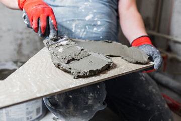 Wall Mural - A low-skilled worker lays tiles poorly - ignorance and inability in the profession