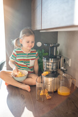 Wall Mural - Little girl making fresh juice sitting on the table in home kitchen