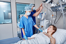 Intensive Care Patient. Nurses Attending To Female Patient In Intensive Care Unit Of Hospital
