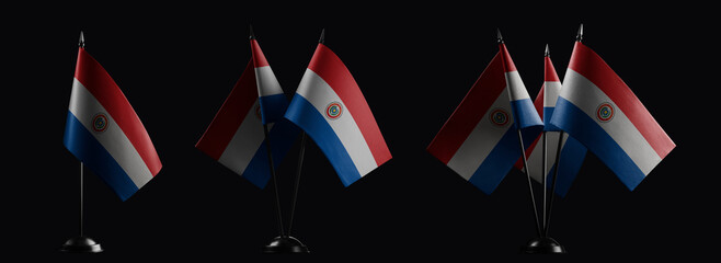 Small national flags of the Paraguay on a black background