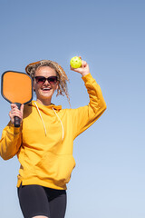 Wall Mural - portrait woman player pickleball game over blue sky, pickleball yellow ball with paddle, outdoor sport leisure activity