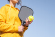 woman playing pickleball game, hitting pickleball yellow ball with paddle, outdoor sport leisure activity