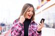© luismolinero - Young pretty Romanian woman at outdoors using mobile phone and doing victory gesture