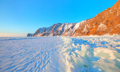 Wall Mural - Beautiful winter landscape of frozen Lake Baikal at sunrise - Snowy ice hummocks with transparent blue piles of ice - Baikal Lake, Siberia