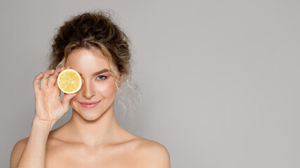 beautiful woman holding lemon half and looking at camera, lady using vitamin c fruit acids for beaut