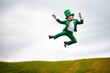 Funny portrait of a jolly leprechaun clicking his heels and jumping outdoors for St. Patrick's Day, generative ai