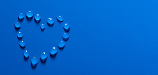 Wall Mural - water drops in heart shape on a blue background