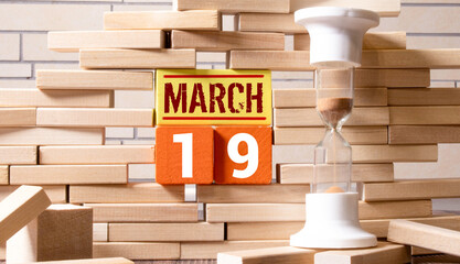 March 19 calendar date text on wooden blocks with blurred park background.